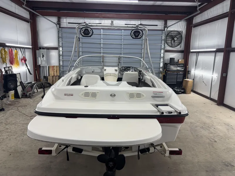 Slide: The Image of 2008 Bayliner Bowrider 185 in a garage, rear view, showcasing interior and swim platform. - 14