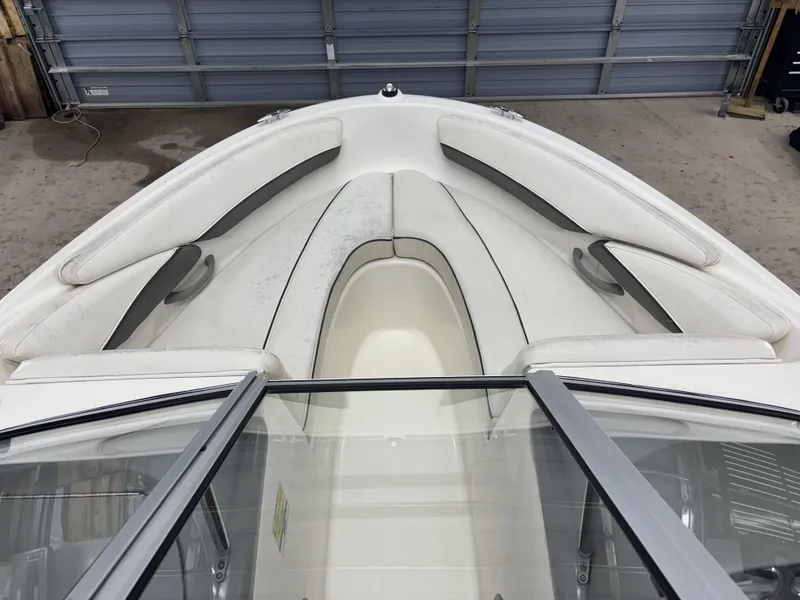 Slide: The Image of 2008 Bayliner Bowrider 185 interior with white seating and windshield in a garage setting. - 7