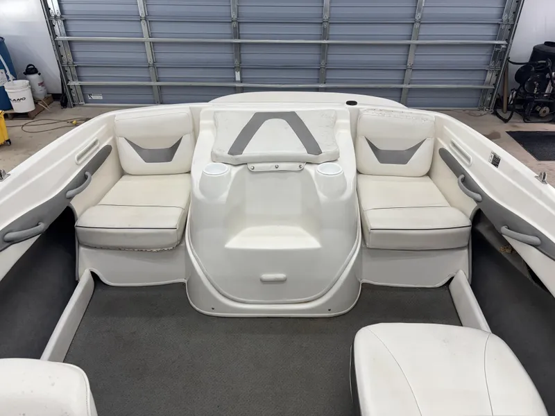 Slide: The Image of 2008 Bayliner Bowrider 185 interior with white seating and gray accents in a garage. - 8