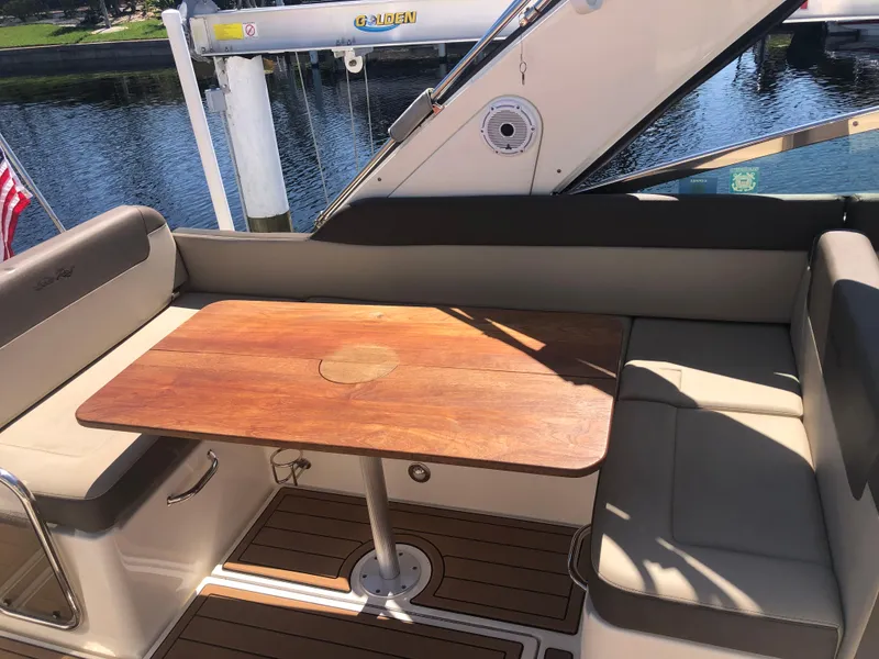 Slide: The Image of 2014 Sea Ray 370 Venture boat interior with wooden table and cushioned seating. - 42