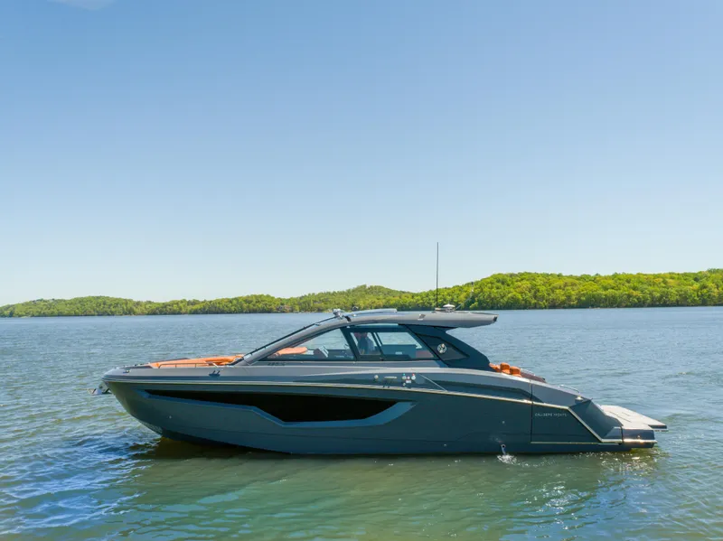 Slide: The Image of 2023 Cruisers Yachts 42 GLS on serene lake with lush green shoreline. - 0