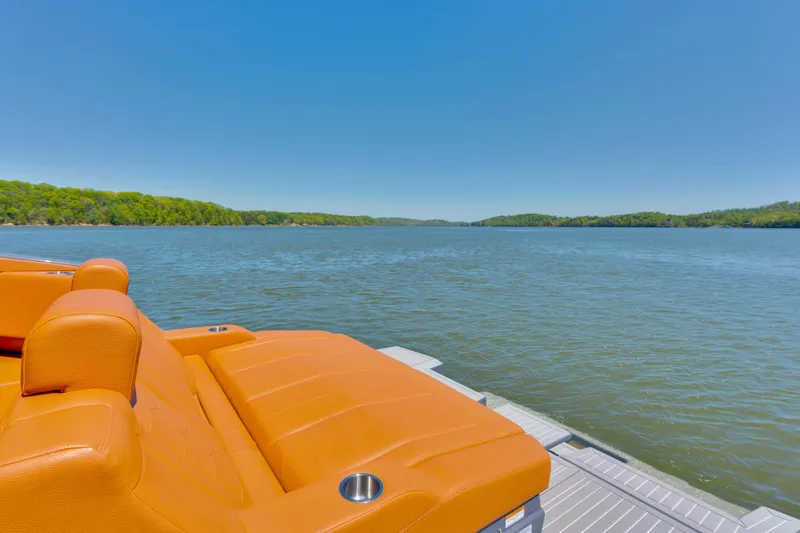 Slide: The Image of 2023 Cruisers Yachts 42 GLS with orange seating, overlooking a serene lake and lush greenery. - 11