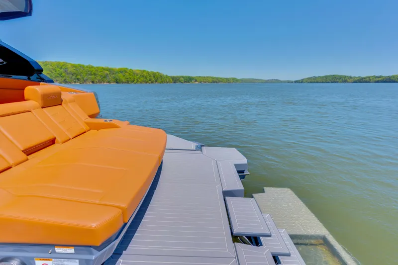 Slide: The Image of 2023 Cruisers Yachts 42 GLS with orange seating, overlooking serene lake and lush greenery. - 12