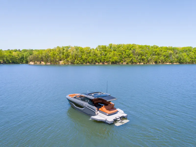 Slide: The Image of 2023 Cruisers Yachts 42 GLS on serene lake with lush green shoreline. - 2