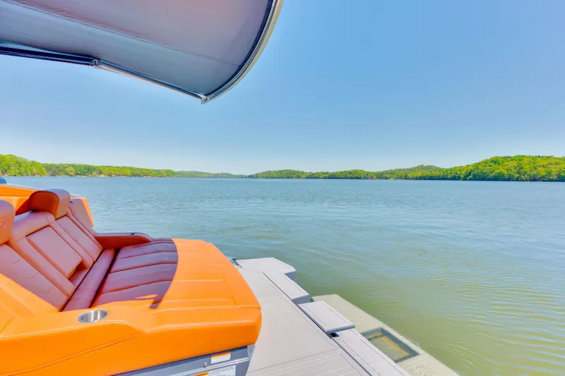 Slide: The Image of 2023 Cruisers Yachts 42 GLS with orange seating, overlooking serene lake and lush greenery. - 38