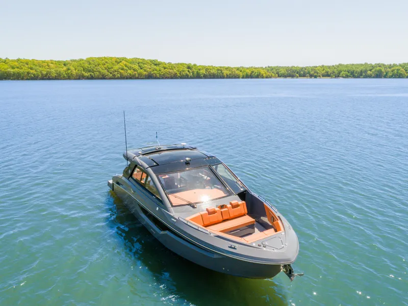 Slide: The Image of 2023 Cruisers Yachts 42 GLS on serene lake with lush green shoreline. - 5