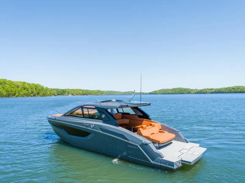 Slide: The Image of 2023 Cruisers Yachts 42 GLS on serene lake with lush green shoreline. - 6