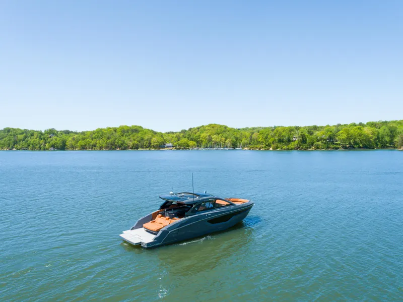 Slide: The Image of 2023 Cruisers Yachts 42 GLS on serene lake with lush green shoreline. - 7