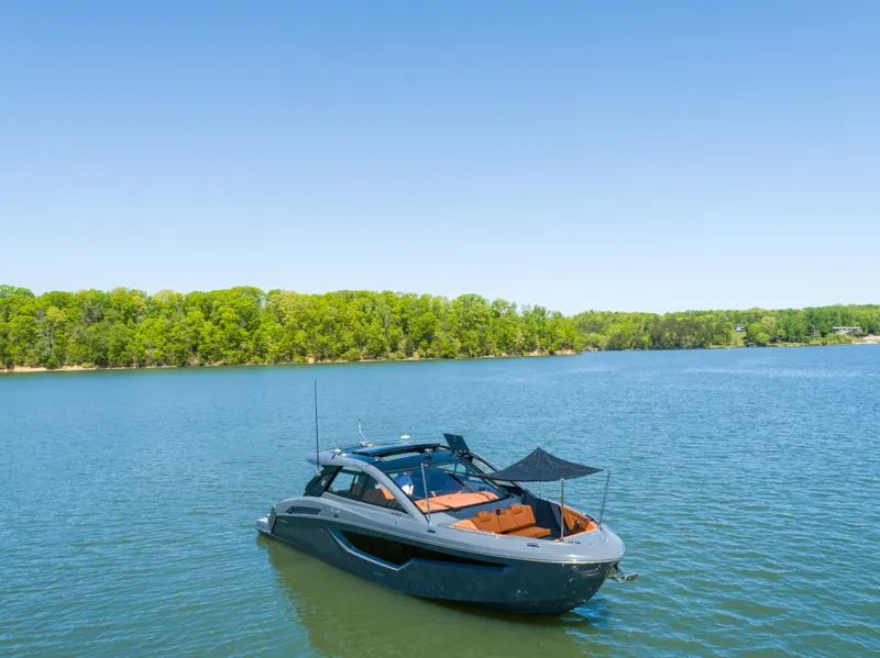 Slide: The Image of 2023 Cruisers Yachts 42 GLS on serene lake with lush green shoreline. - 8