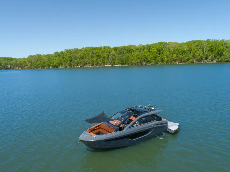 Slide: The Image of 2023 Cruisers Yachts 42 GLS on serene lake with lush green shoreline. - 9