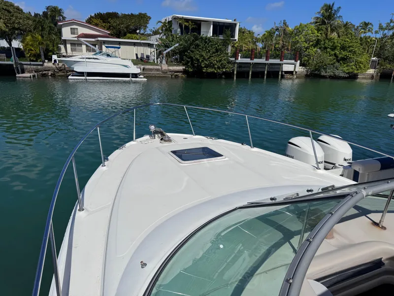 Slide: The Image of 2004 Sea Ray 290 Amberjack boat docked in a serene waterfront setting. - 10