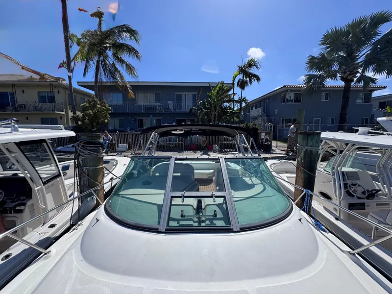 Slide: The Image of 2004 Sea Ray 290 Amberjack docked, surrounded by palm trees and buildings under a clear blue sky. - 11