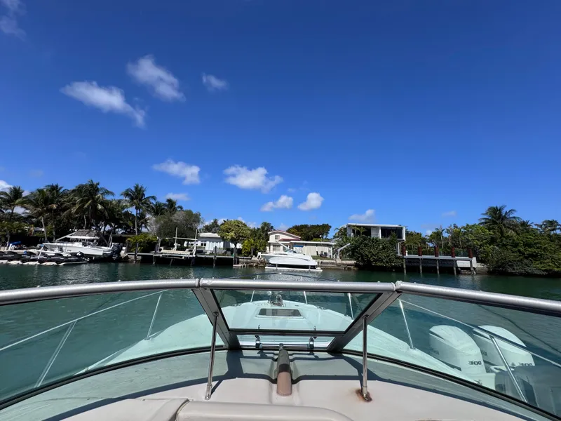 Slide: The Image of 2004 Sea Ray 290 Amberjack cruising in a scenic waterfront area under a clear blue sky. - 9