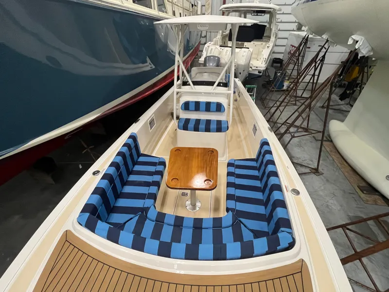 Slide: The Image of 2021 Vanquish 26 boat with blue striped seating and wooden table in a storage facility. - 10