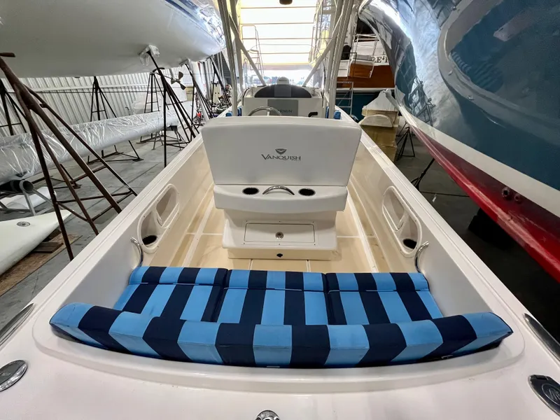 Slide: The Image of 2021 Vanquish 26 boat interior with blue striped seating in a storage facility. - 14