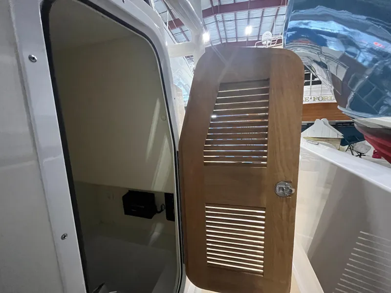 Slide: The Image of 2021 Vanquish 26 boat interior with wooden louvered door in a showroom. - 15