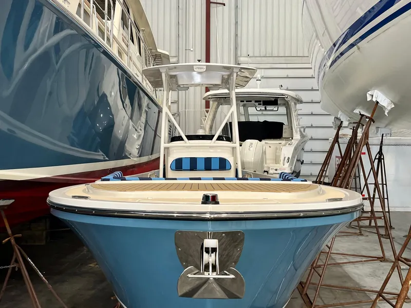 Slide: The Image of 2021 Vanquish 26 boat in storage, blue hull, surrounded by other boats. - 2