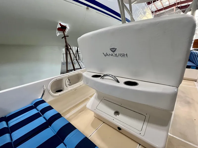 Slide: The Image of 2021 Vanquish 26 boat interior with blue striped seating and storage compartment. - 20