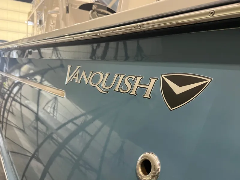 Slide: The Image of 2021 Vanquish 26 boat with blue hull and logo in a showroom. - 24