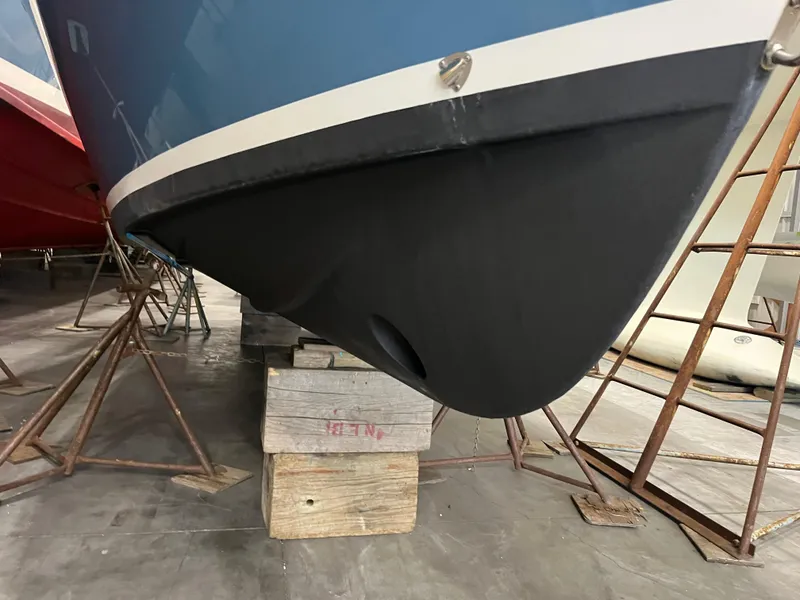 Slide: The Image of 2021 Vanquish 26 boat hull in storage, supported by wooden blocks. - 25
