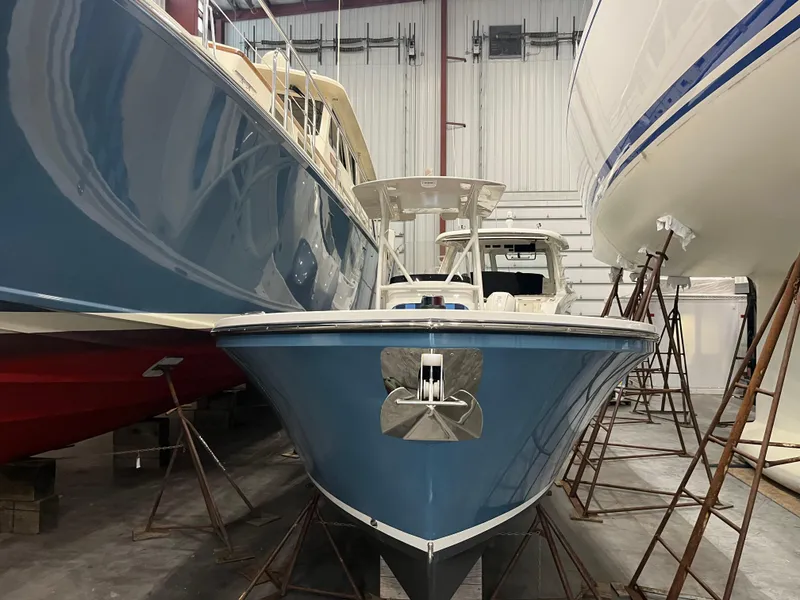 Slide: The Image of 2021 Vanquish 26 boat in storage, blue hull, indoor facility. - 5
