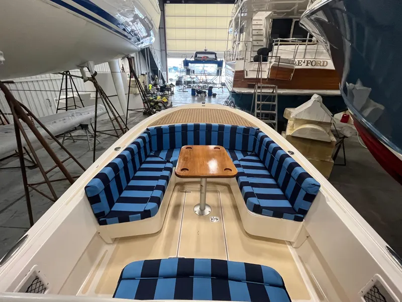 Slide: The Image of Vanquish 26 boat interior with blue striped seating and wooden table, 2021 model. - 8