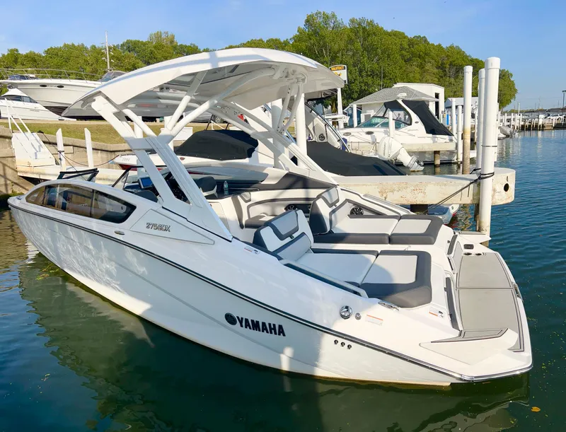 Slide: The Image of 2023 Yamaha Boats 275 SDX docked, sleek design, white exterior, spacious seating, sunny marina setting. - 5