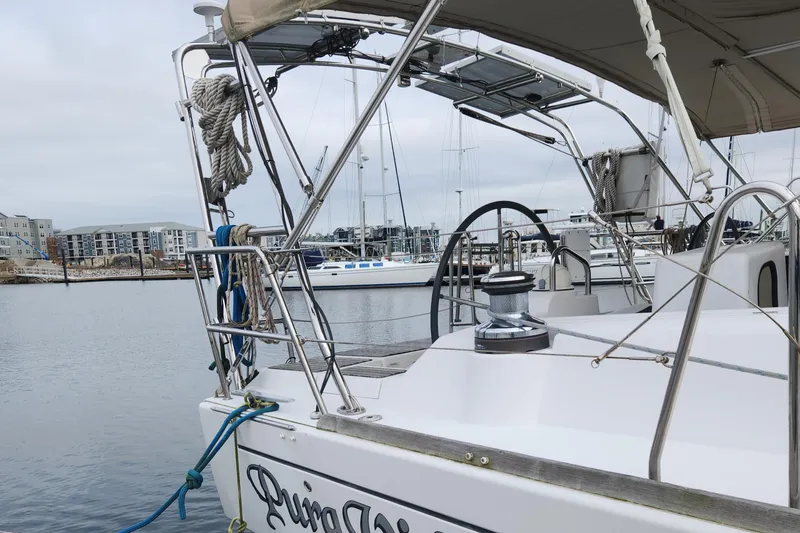 Slide: The Image of Beneteau Oceanis 48 sailboat docked in marina, showcasing deck and steering wheel, 2013 model. - 10