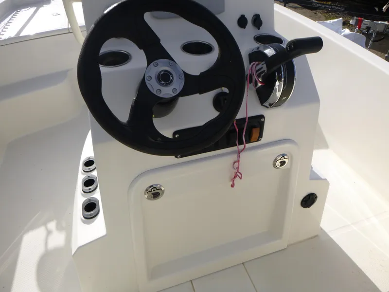 Slide: The Image of 2022 Mako 19CC boat steering console with black wheel and controls. - 23