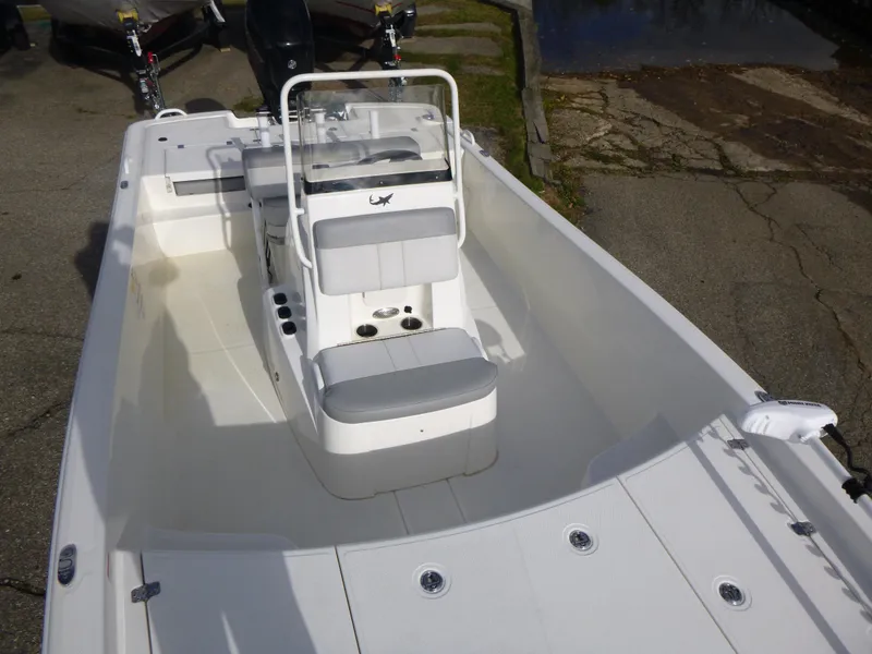 Slide: The Image of 2022 Mako 19CC boat interior with seating and console, parked on pavement. - 32