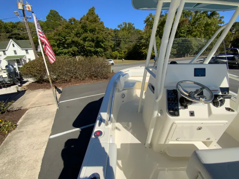 Slide: The Image of 2025 Cobia 220 Center Console boat parked outdoors, showcasing steering console and seating. - 21