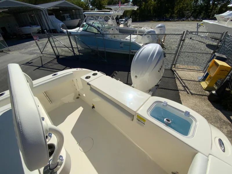 Slide: The Image of 2025 Cobia 220 Center Console boat in a marina, showcasing interior and outboard motor. - 34