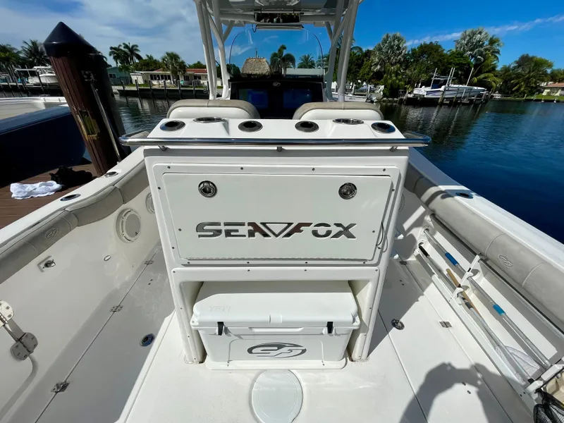 Slide: The Image of 2019 Sea Fox 288 Commander boat interior with storage and seating, docked by a scenic waterfront. - 32