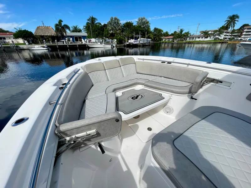 Slide: The Image of 2019 Sea Fox 288 Commander boat with spacious seating and table, docked by a scenic waterfront. - 6