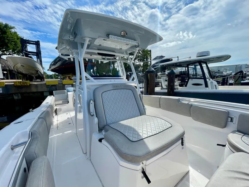 Slide: The Image of 2019 Sea Fox 288 Commander boat with cushioned seating, docked under a partly cloudy sky. - 8
