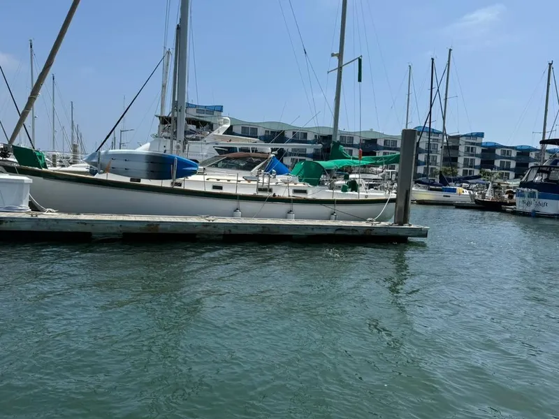 Slide: The Image of 1982 Pearson Ketch sailboat docked in a marina with waterfront buildings. - 1