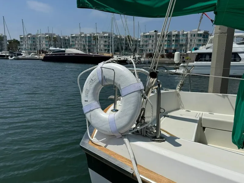 Slide: The Image of 1982 Pearson Ketch sailboat docked with life preserver, marina in background. - 12