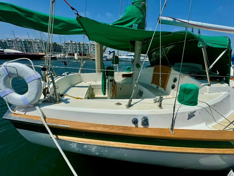 Slide: The Image of 1982 Pearson Ketch sailboat with green canopy docked in marina. - 13