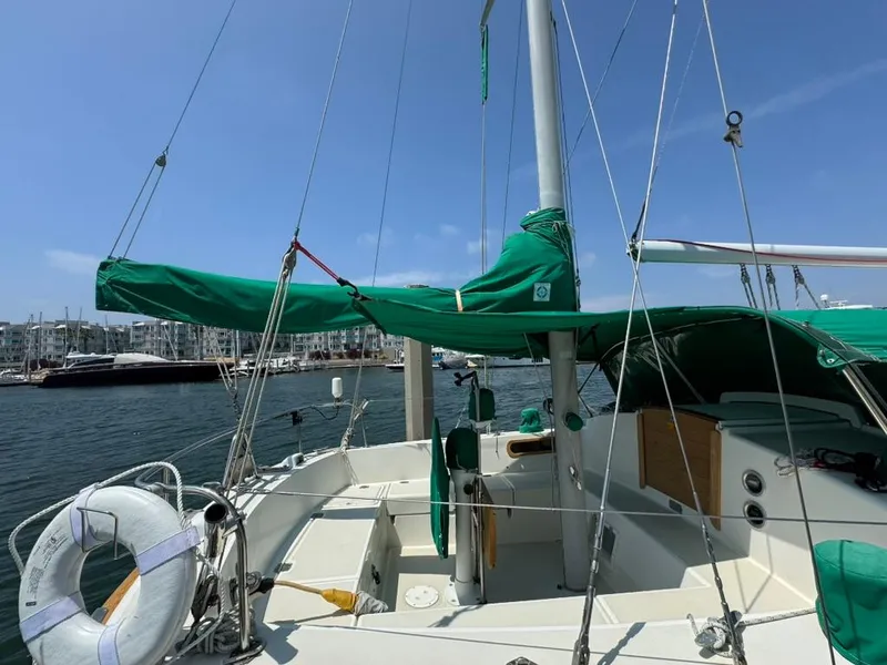 Slide: The Image of 1982 Pearson Ketch sailboat with green covers docked in marina. - 14