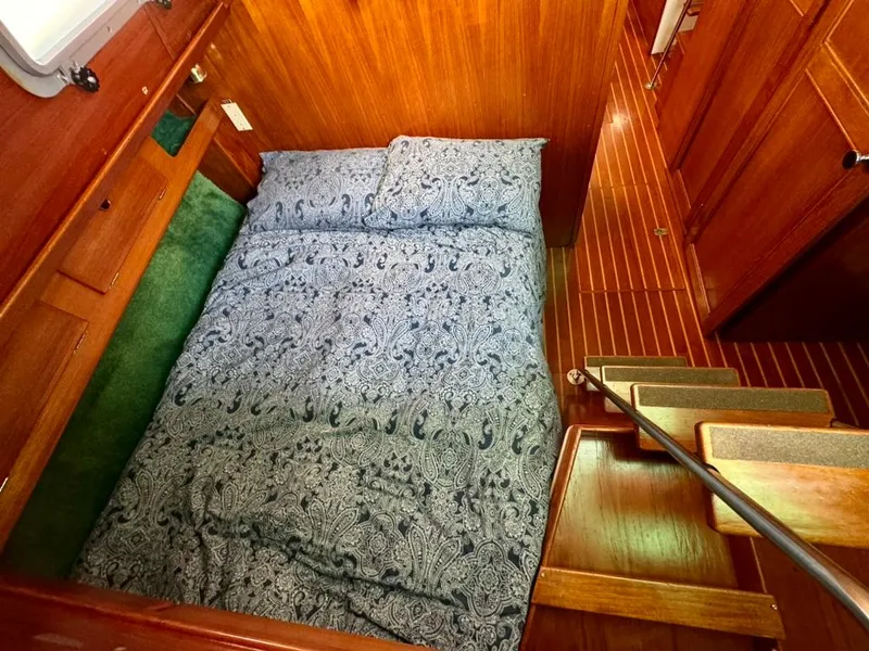 Slide: The Image of Cozy cabin interior of 1982 Pearson Ketch with patterned bedding and wooden finishes. - 18