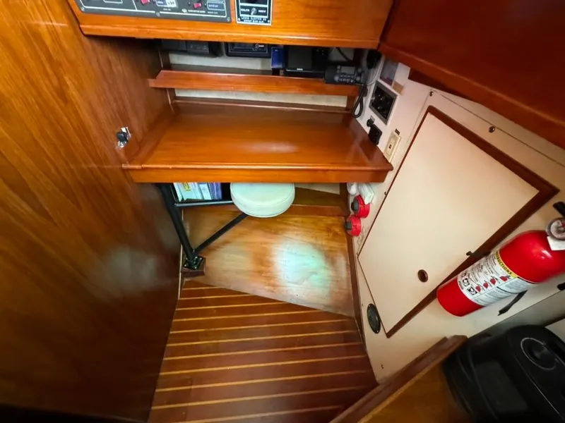 Slide: The Image of 1982 Pearson Ketch interior with wooden desk, fire extinguisher, and storage shelves. - 21
