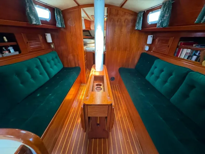 Slide: The Image of Interior of 1982 Pearson Ketch sailboat with green cushioned seating and wooden finishes. - 22