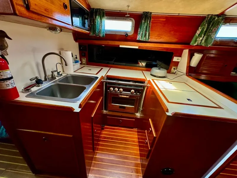 Slide: The Image of 1982 Pearson Ketch yacht kitchen with wood cabinetry, dual sink, and stove. - 23