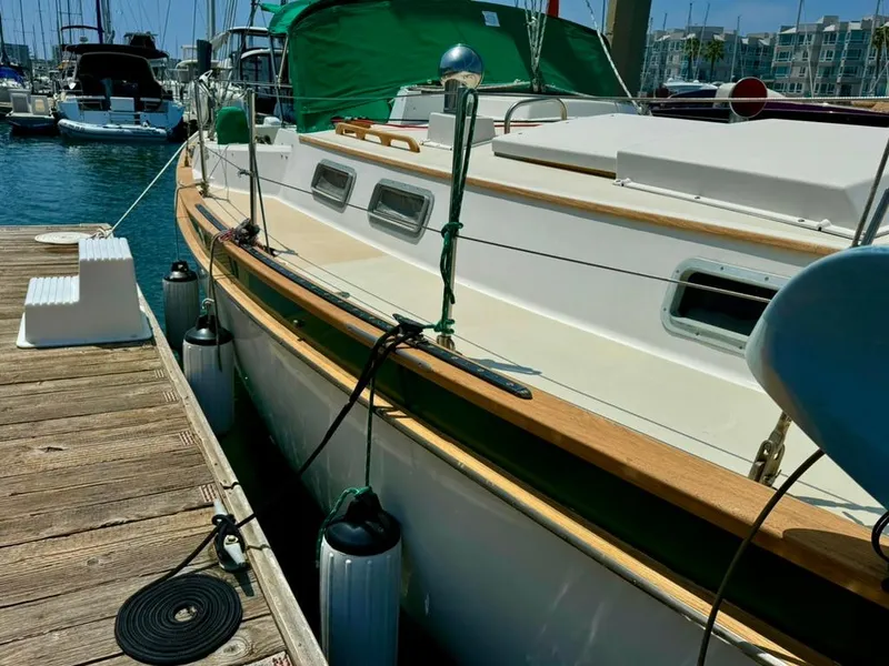 Slide: The Image of 1982 Pearson Ketch sailboat docked at marina, featuring green canopy and wooden deck. - 3