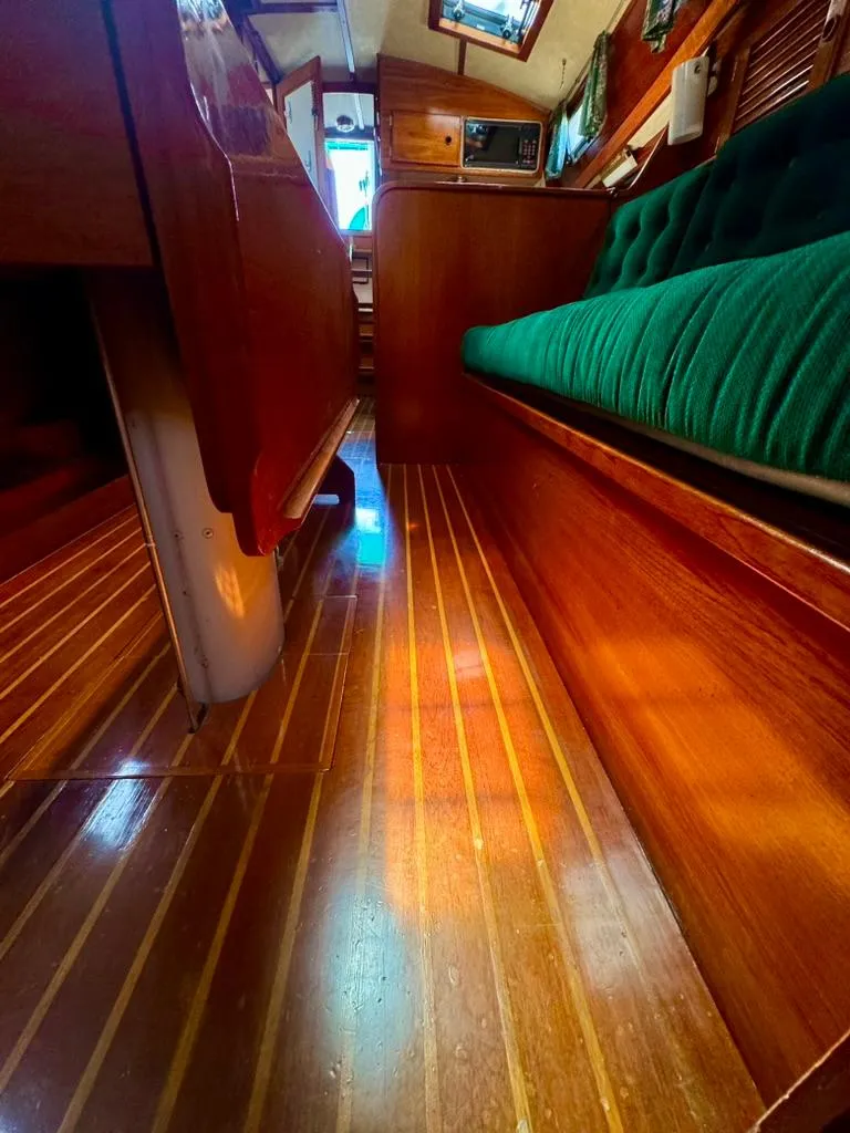 Slide: The Image of Interior of 1982 Pearson Ketch sailboat with wooden flooring and green cushioned seating. - 35