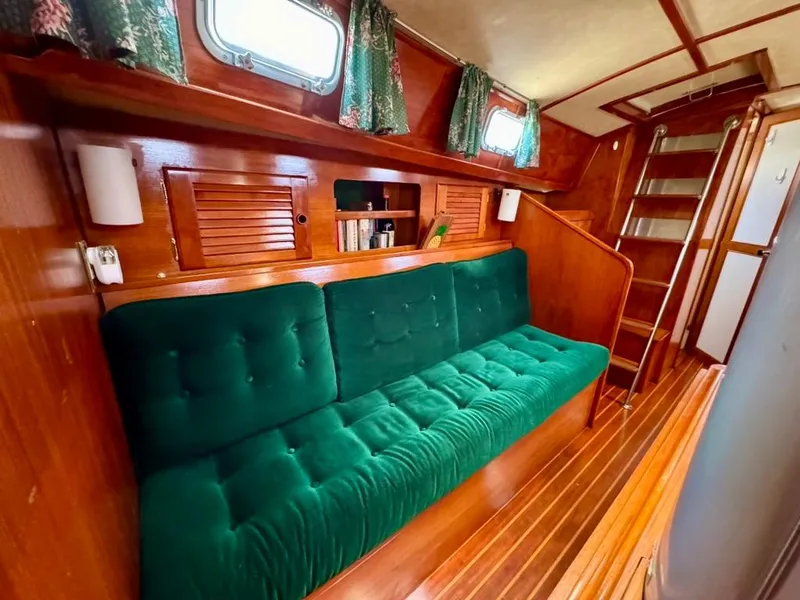 Slide: The Image of Interior of 1982 Pearson Ketch sailboat with green cushioned seating and wooden accents. - 36