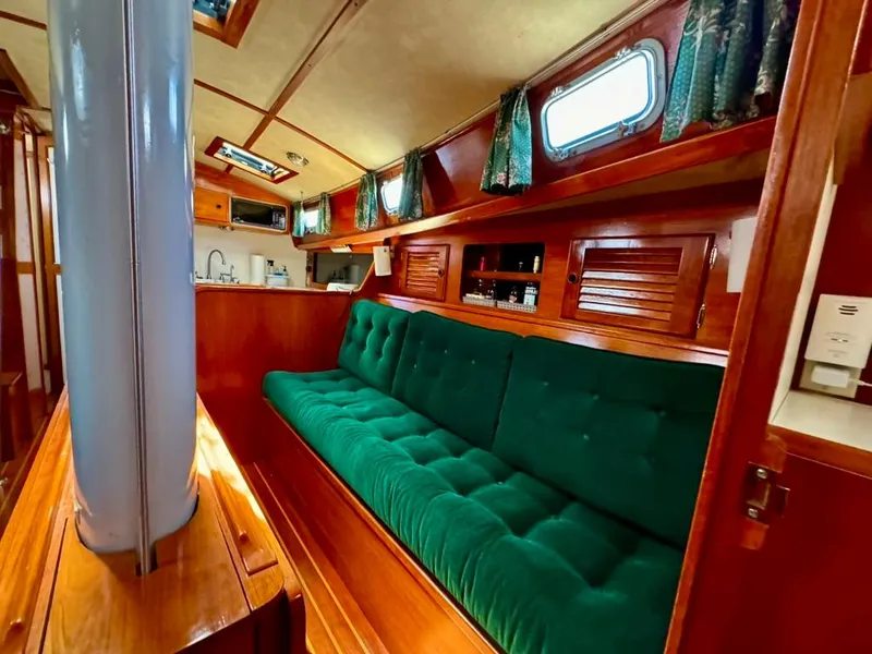 Slide: The Image of Interior of 1982 Pearson Ketch sailboat with green cushioned seating and wooden finishes. - 37