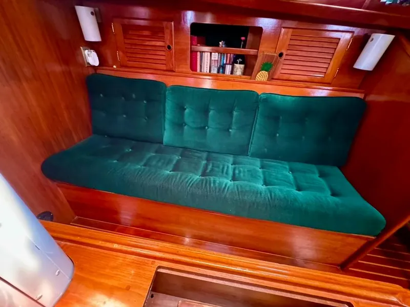 Slide: The Image of 1982 Pearson Ketch interior with green cushioned seating and wooden cabinetry. - 40