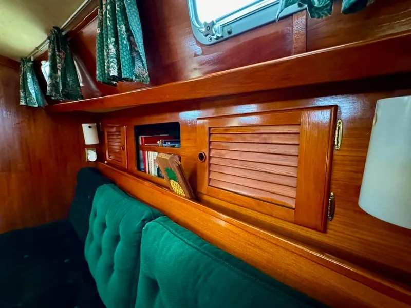 Slide: The Image of Interior of 1982 Pearson Ketch with wooden cabinets and green cushions. - 42