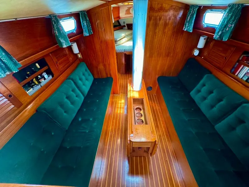 Slide: The Image of Interior of 1982 Pearson Ketch sailboat with green cushioned seating and wooden paneling. - 43
